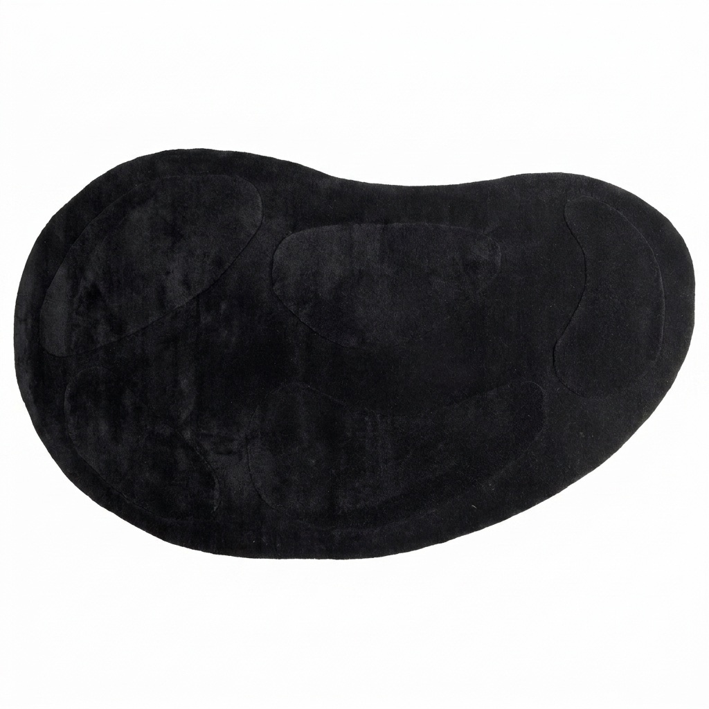 Tapis noir en laine et coton, silhouette galet organique asymétrique avec motifs sculptés ton sur ton, vue de dessus fond blanc