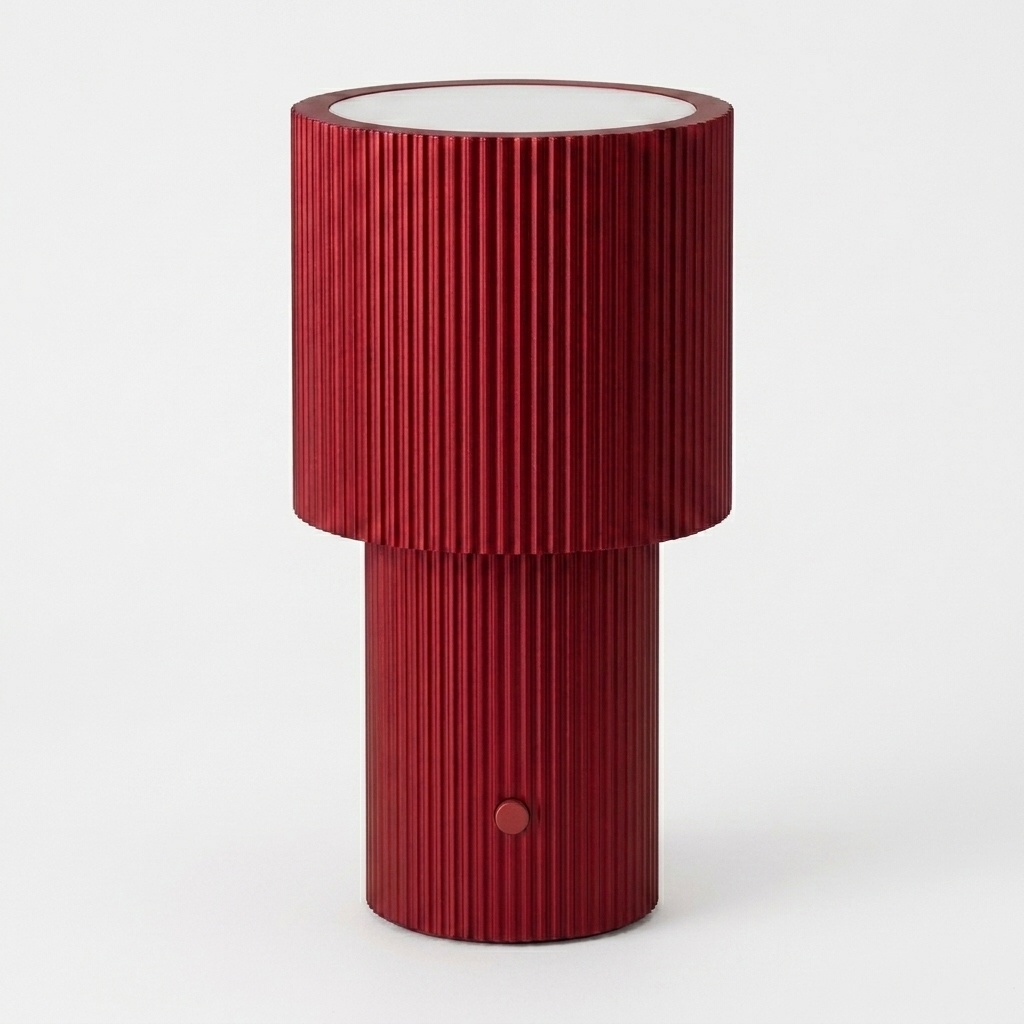 Lampe à poser portable en aluminium anodisé rouge, silhouette à deux cylindres cannelés, fond neutre clair.