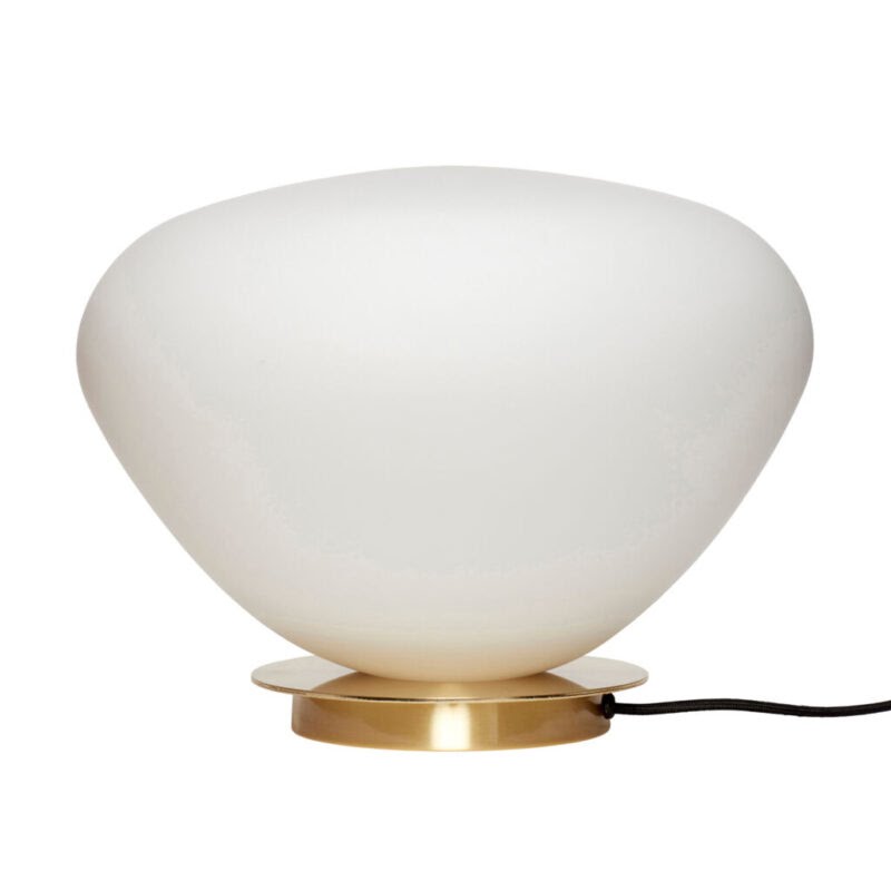 Lampe à poser galet en verre opalin blanc sur base ronde en laiton brossé, sur fond clair neutre