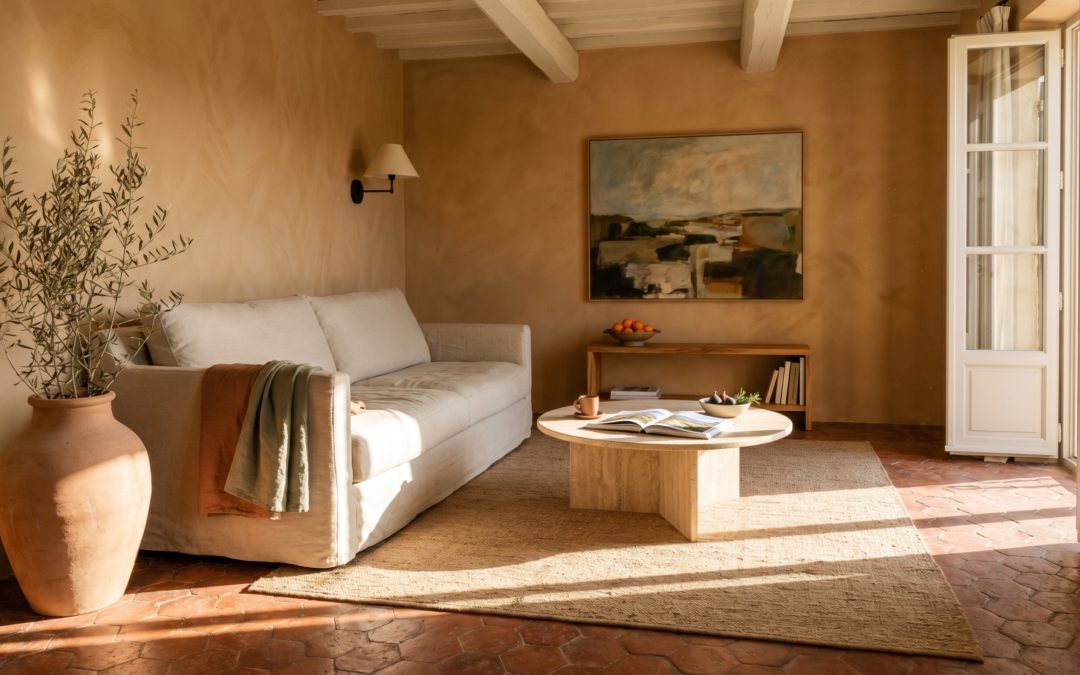 Salon Sunbaked Méditerranéen dans un mas de Provence restauré, mur en limewash terracotta, canapé lin écru avec plaid rouille, table basse ronde en bois huilé, jarre terre cuite avec branche d'olivier et tomettes hexagonales patinées sous lumière du sud rasante