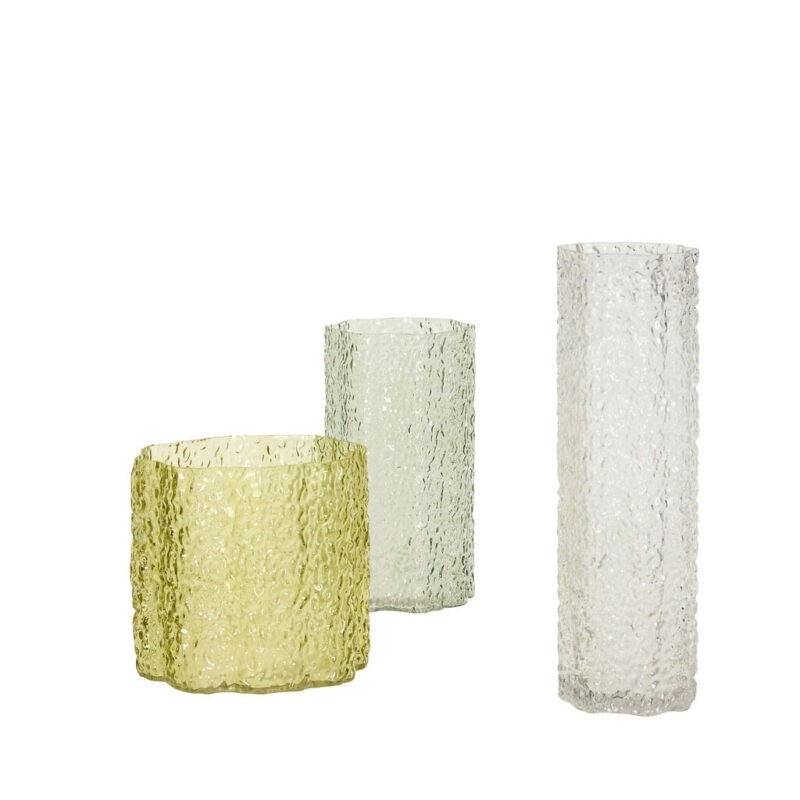 Trois vases cylindriques en verre soufflé texturé, déclinés du transparent au vert pâle puis au vert olive, sur fond blanc