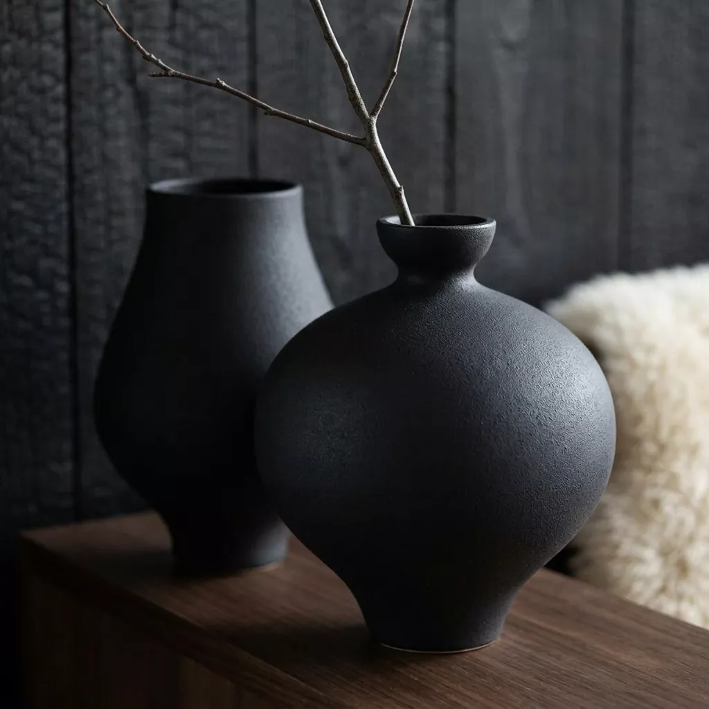 Duo de vases céramique noire mate sur console noyer, fond bois brûlé yakisugi et laine mouton, ambiance japandi intime
