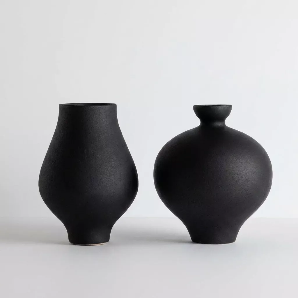 Duo de vases en céramique noire mate engobe, silhouettes contrastées sur fond neutre gris, panse sphérique et col effilé