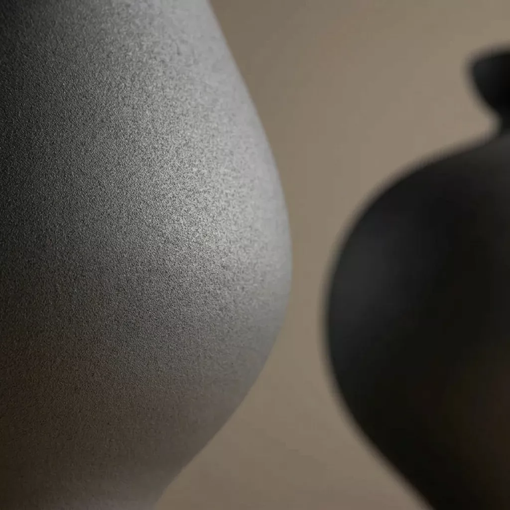 Détail de surface céramique engobe mat, grain sableux fin révélé par lumière rasante, panse du vase Zian au premier plan