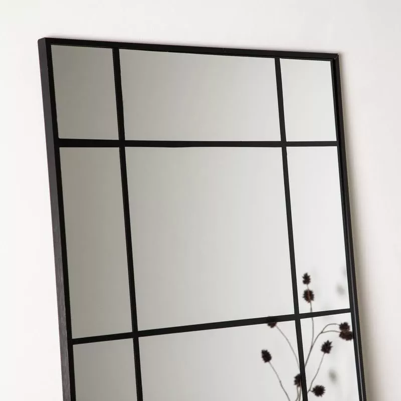 Gros plan cadre aluminium noir mat et quadrillage 3×4 du miroir verrière Isak, reflet branche séchée sur fond clair