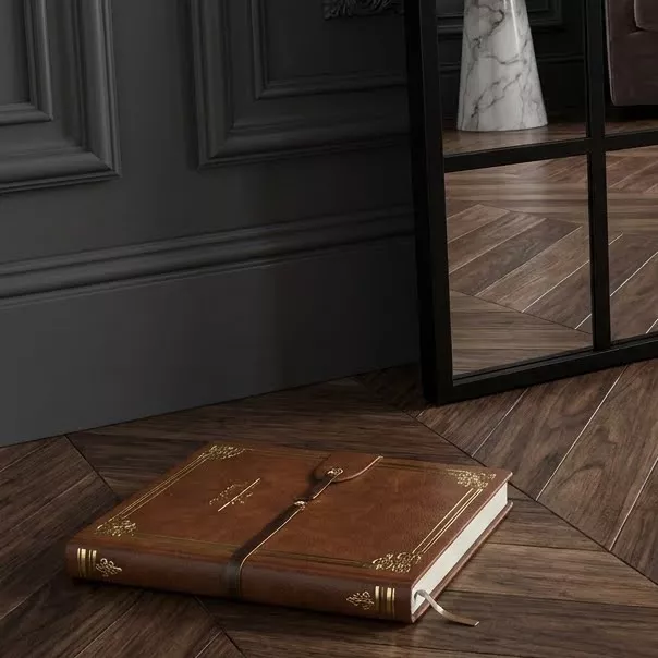 Détail base du miroir verrière Isak sur parquet chevrons noyer, livre cuir doré au sol, boiserie grise anthracite
