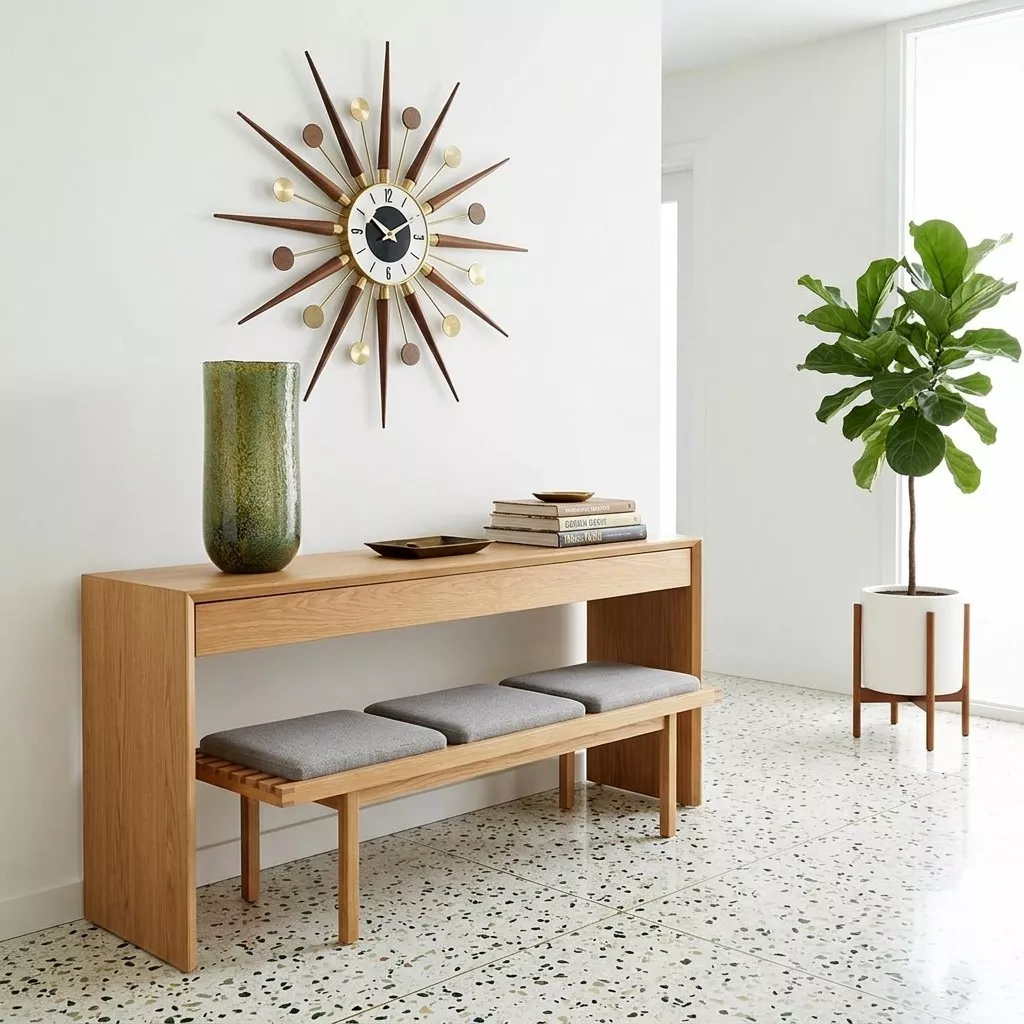 Vase cylindrique en verre vert olive sur une console en bois clair, horloge soleil au mur et grande plante verte en pot