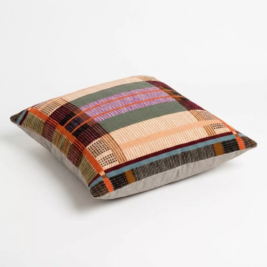 Coussin brodé multicolore en coton, vue de trois-quarts, motif patchwork bandes pêche, terracotta et aubergine, fond neutre
