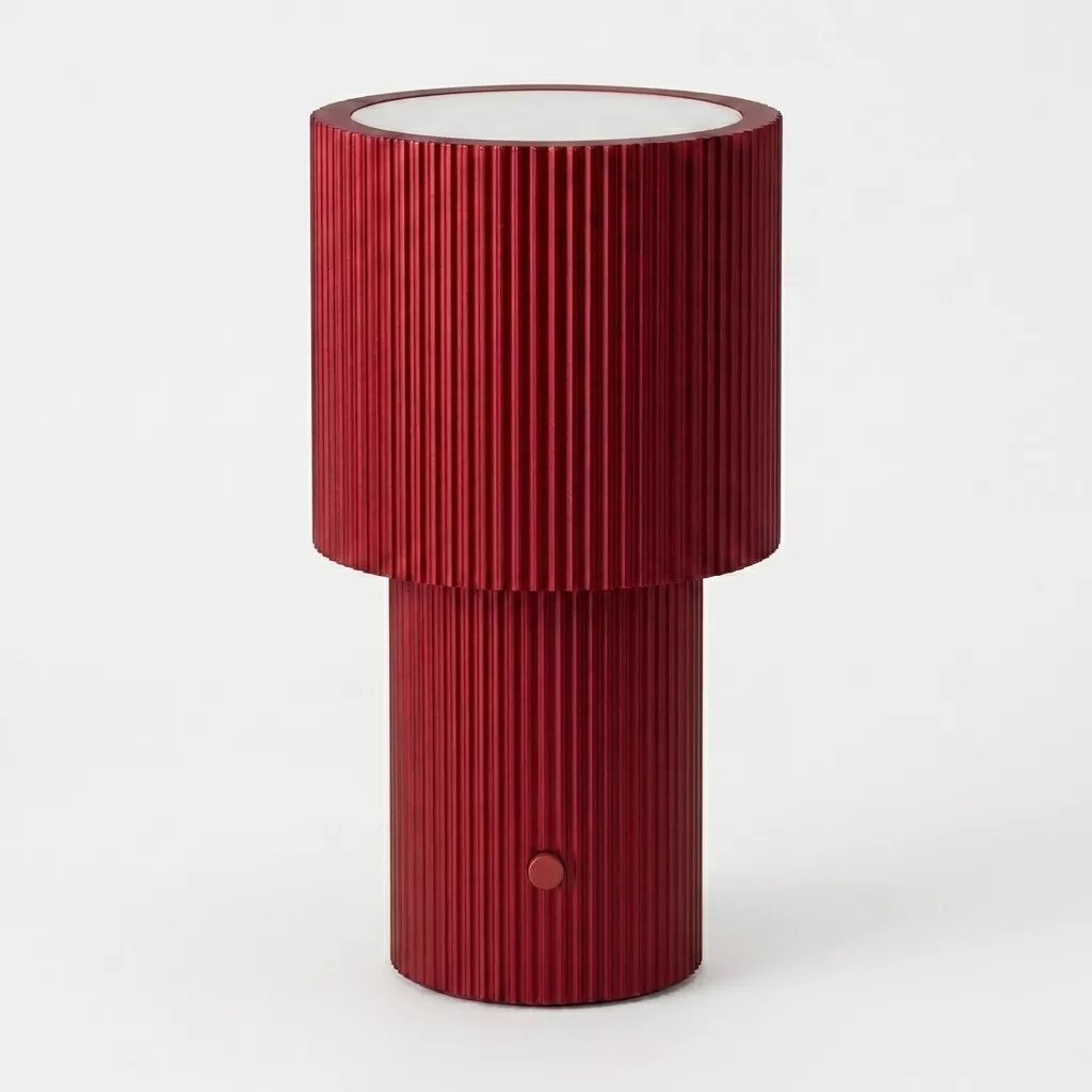 Lampe à poser portable en aluminium anodisé rouge, silhouette à deux cylindres cannelés, fond neutre clair.
