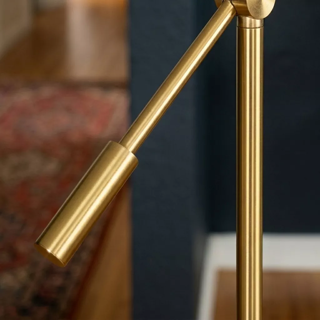 Détail de la tête cylindrique en laiton poli à collet cannelé et du bras articulé, mur bleu nuit et tapis à motif en flou