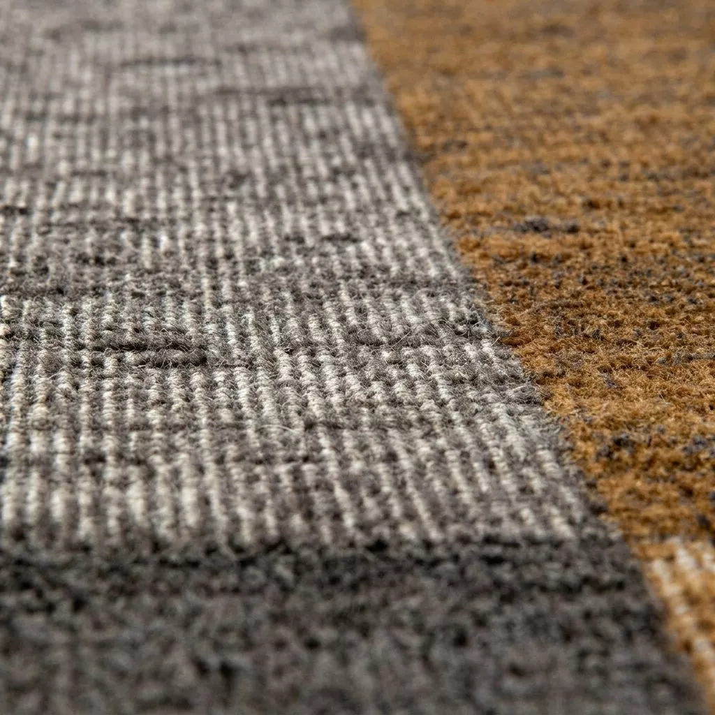 Détail du tissage jacquard à poils ras, jonction du gris béton chiné et de l'ocre moutarde, fibre dense et mate