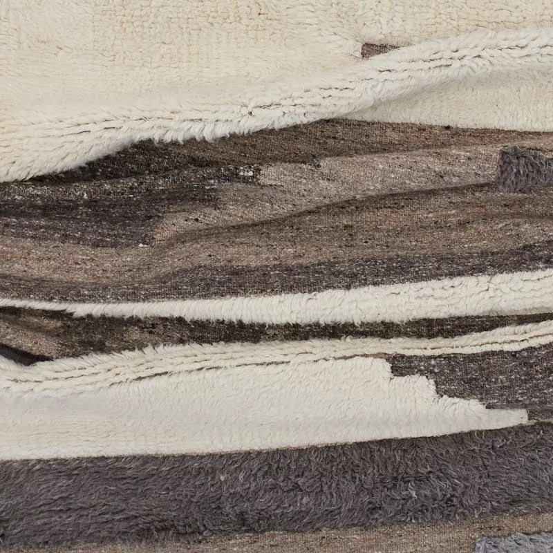 Détail laine : bandes shaggy ivoire et kilim gris-brun, découpes en escalier irrégulier, contraste de hauteur et de texture