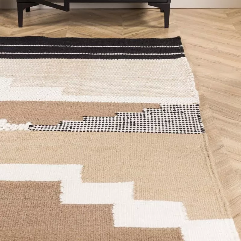 Vue rapprochée bande noire et grille tissée noir et blanc du tapis kilim laine, posé sur parquet chevron clair
