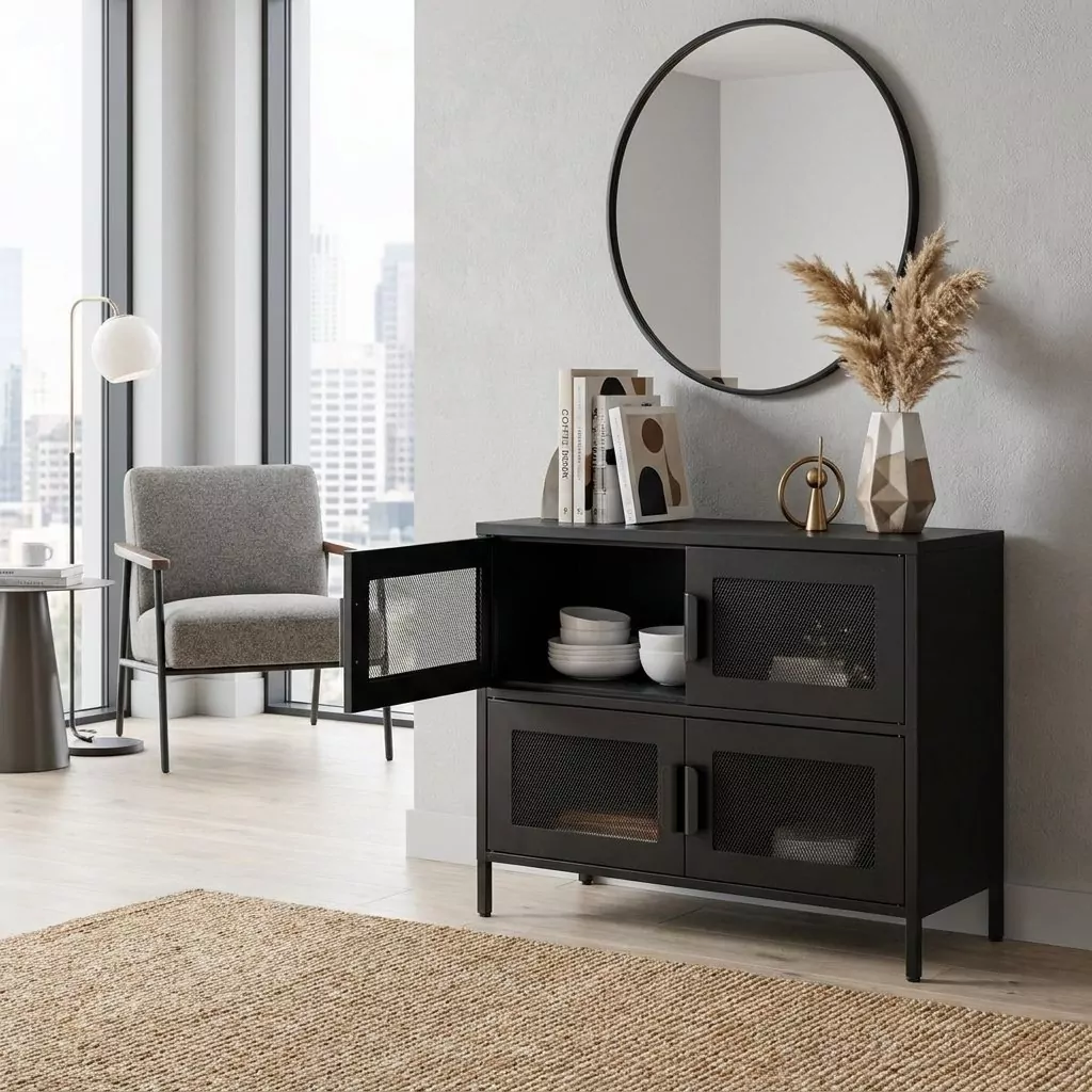 Buffet bas en acier noir mat à portes en grillage losange dans un salon urbain, miroir rond noir et fauteuil gris