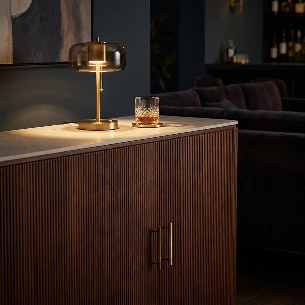 Buffet en noyer cannelé et plateau effet marbre, ambiance feutrée, lampe à dôme de verre dorée et mur bleu nuit
