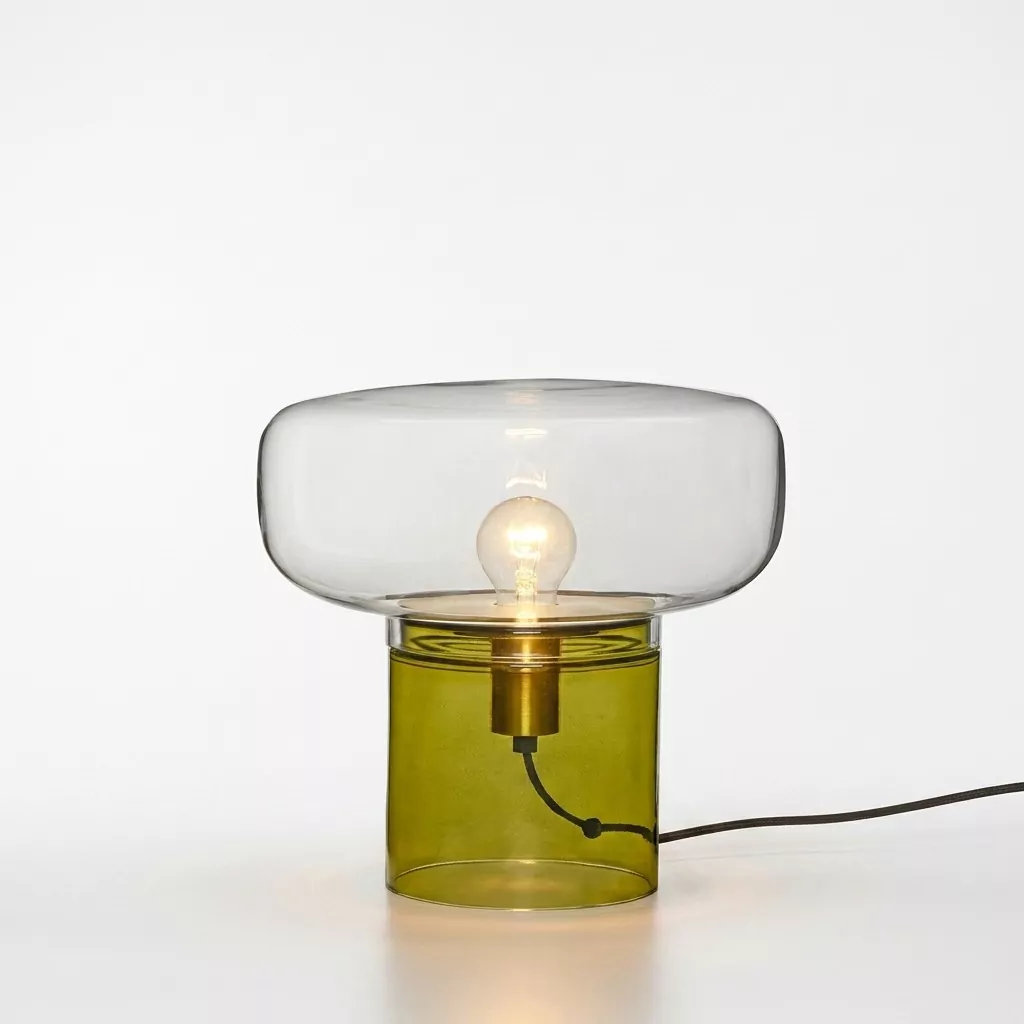 Lampe à poser allumée en verre soufflé, base cylindrique verte et dôme transparent, ampoule visible et cordon textile noir