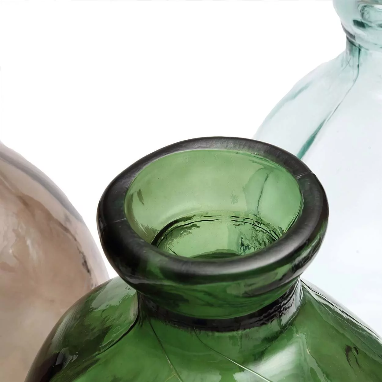 Gros plan sur le col en verre vert translucide d'un vase soufflé à la main, autres pièces en verre floues derrière