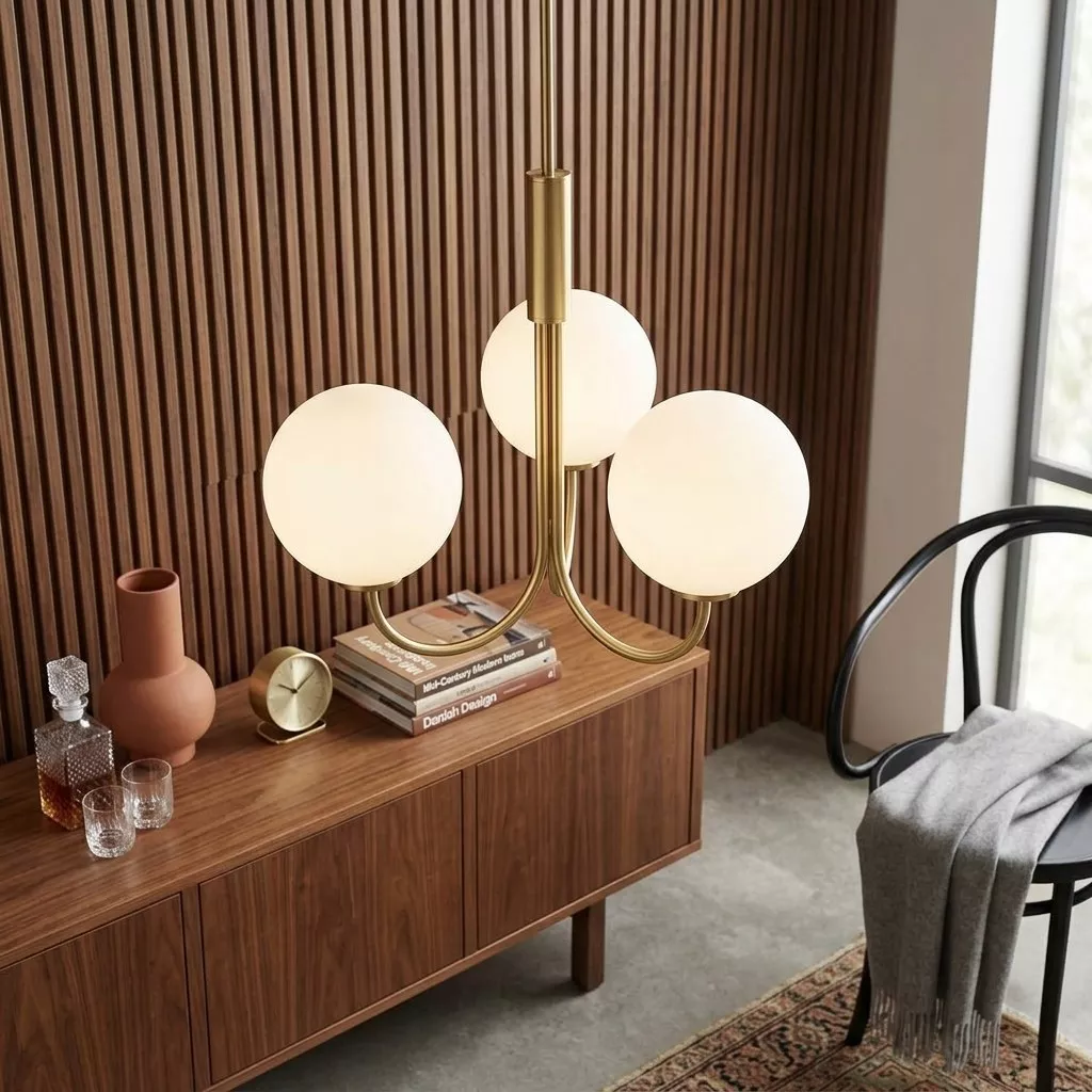 Détail du lustre trois globes opalin laiton satiné, bras arqués et globes sphériques en avant d'une enfilade bois foncé