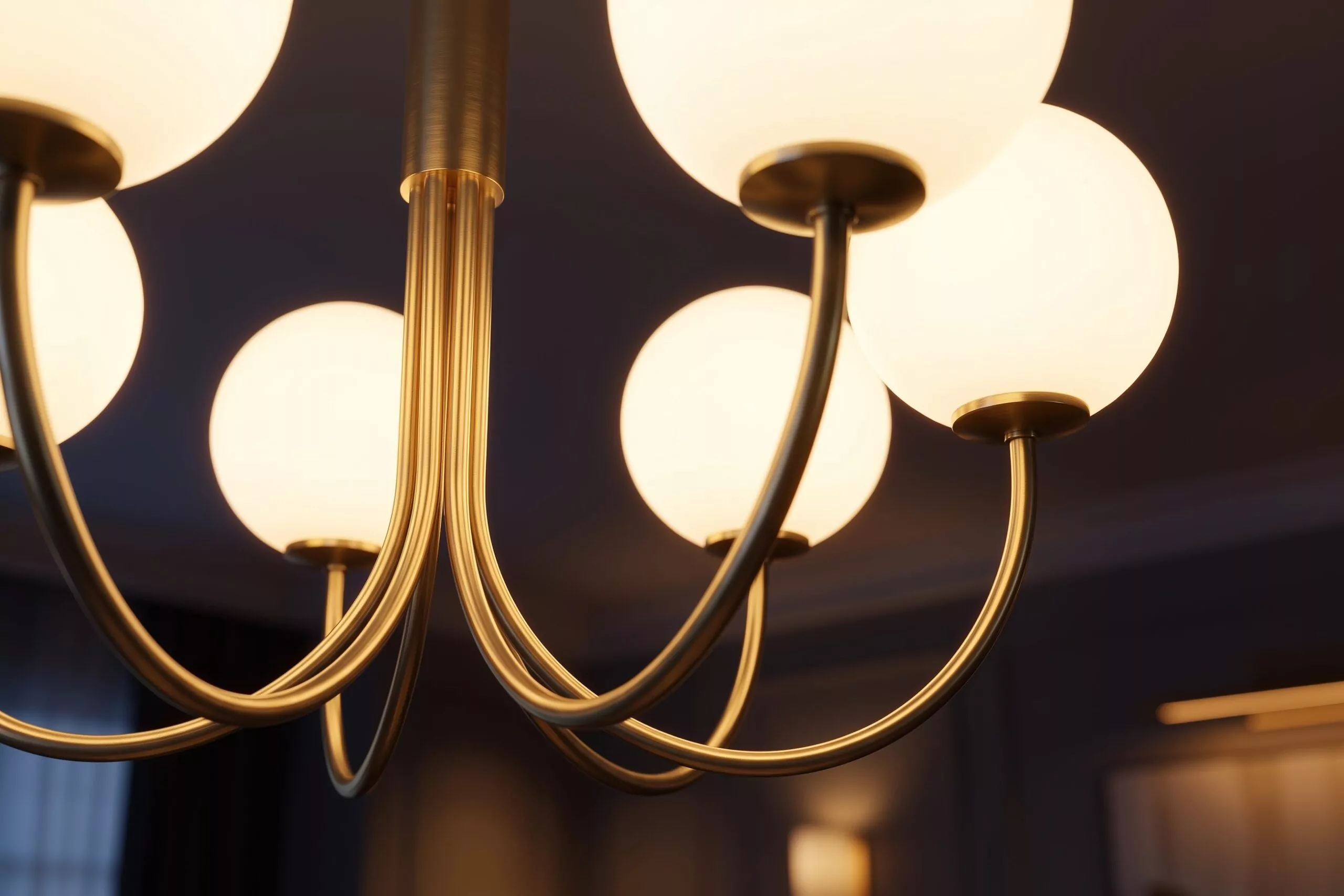 Lustre art déco à globes en verre opalin et bras courbes en laiton satiné, allumé dans un séjour au crépuscule