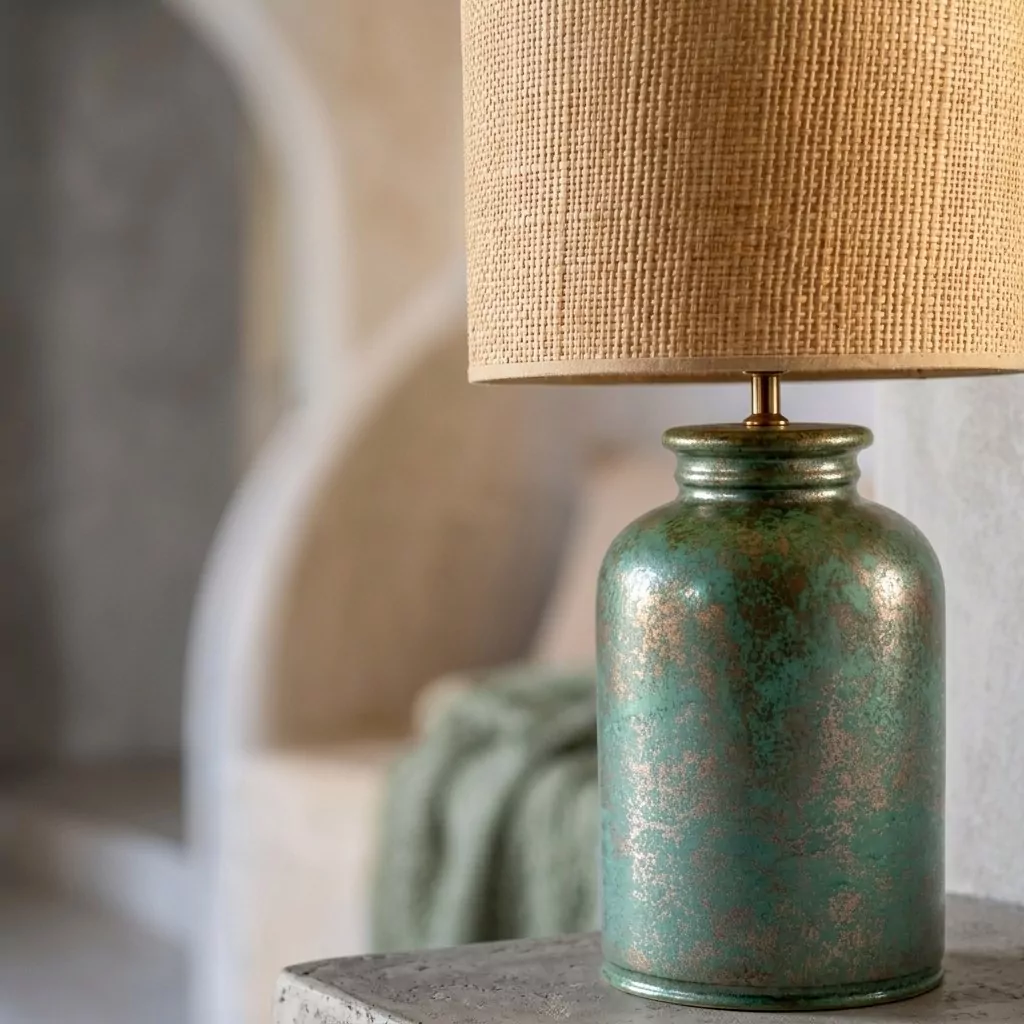 Grande lampe à poser en céramique métallisée vue de près, base vert turquoise oxydé à reflets dorés et abat-jour en raffia